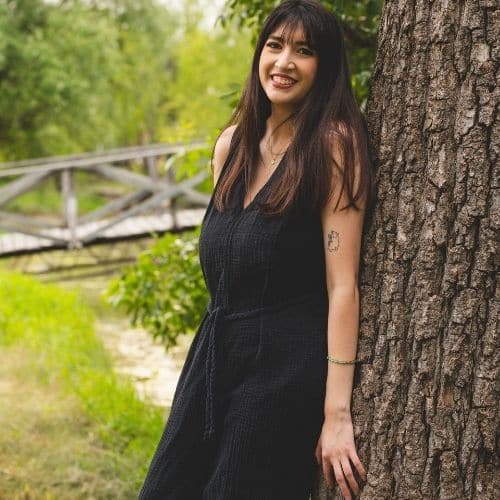 Sofia leaning against a tree and smiling at the camera.